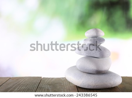 Pyramid of spa stones on wooden surface and bright blurred background
