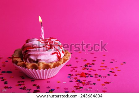 Birthday cup cake with candle and colorful stars on pink background