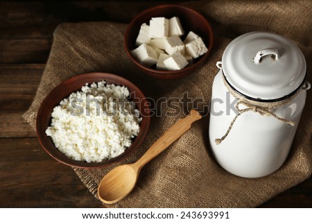 Milk can with cottage cheese on wooden background