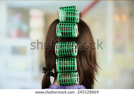Long female hair during hair dressing with curler, close-up, on light background