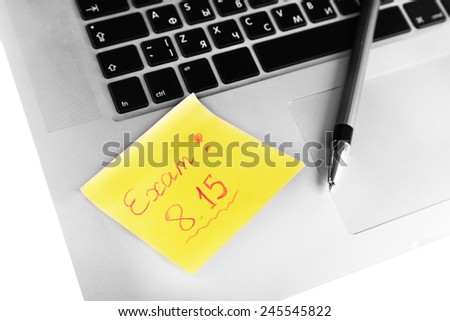 Laptop with sheet of paper and note Exam, on white background