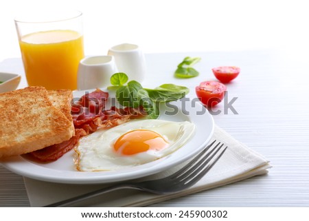 Bacon and eggs on color wooden table and white background