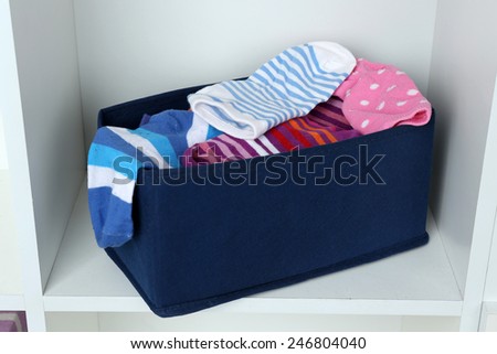 Different socks in textile box on closet background