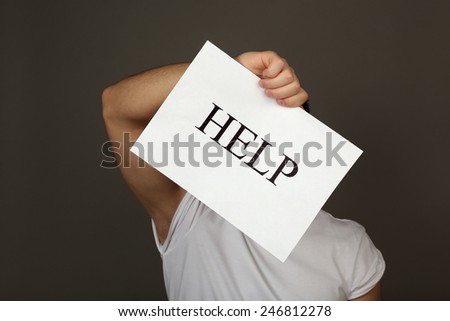 Sheet of paper with Help sign in male hand on dark background