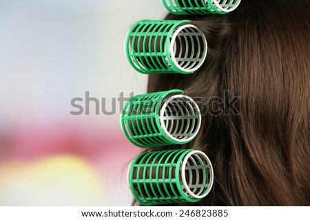 Long female hair during hair dressing with curler, close-up, on light background