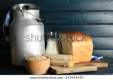Retro can for milk with fresh bread and glass jug of milk on wooden background. Bio products concept