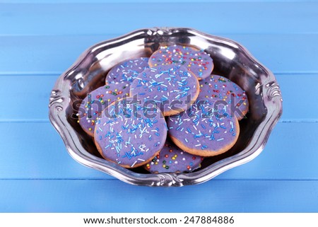 Group of glazed cookies in metal bowl on color wooden planks background
