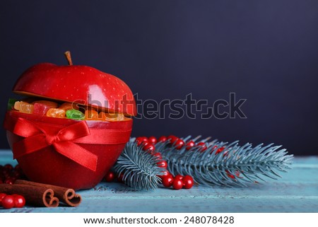 Christmas red apple stuffed with dried fruits on color wooden table and dark background