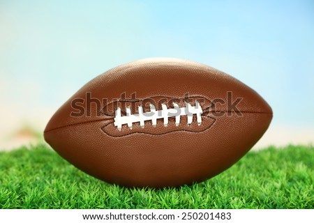 American football on field on green grass, on blue sky background