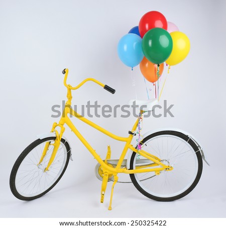 Yellow bicycle with balloons isolated on white