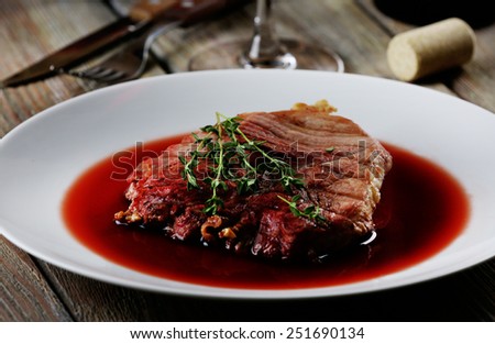 Grilled steak in wine sauce on plate on table close up