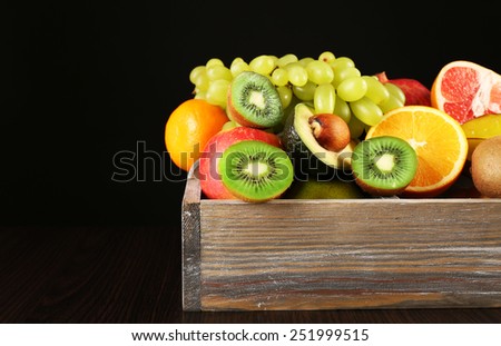 Assortment of fruits in box on black background