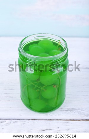 Homemade jar of green maraschino cherry on wooden table and color wall background