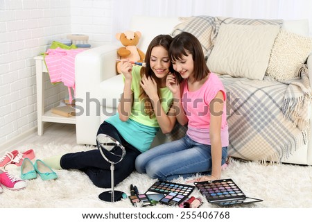 Two girls  with decorative cosmetics on home interior background