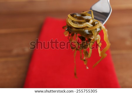 Seaweed on fork with red napkin and wooden table background