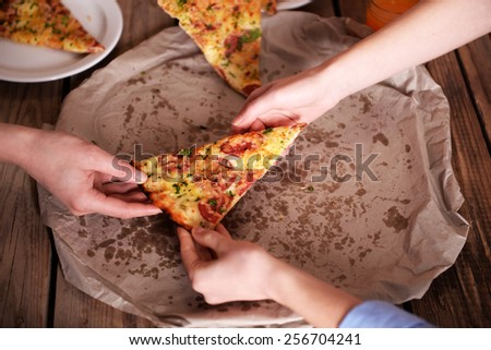 Friends hands taking slice of pizza