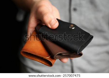 Man holding hand made leather wallets on black background