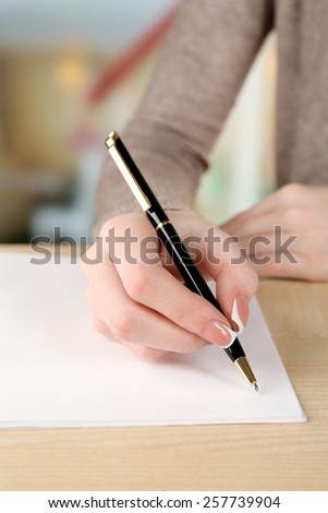 Female hand with pen writing on paper, closeup