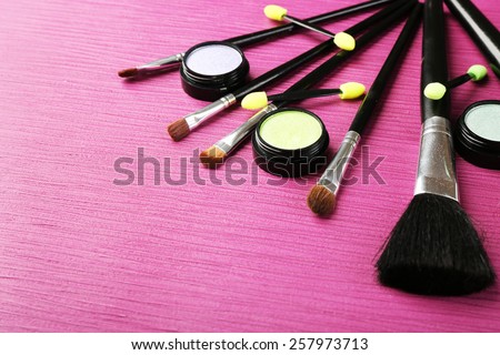 Set of makeup brushes on pink wooden table background