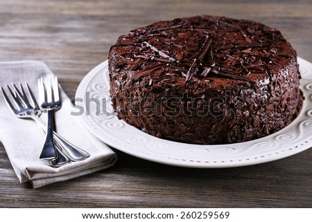 Delicious chocolate cake in plate with forks on wooden table background