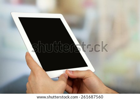 Hands using tablet PC on light blurred background