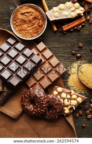 Still life with set of chocolate, nuts and spices on wooden table, top view