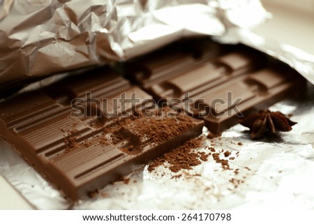 Bar of chocolate with cocoa and star anise on foil, closeup