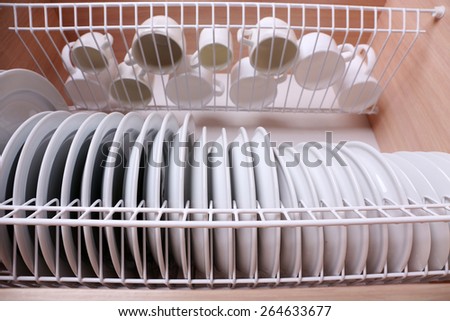 Clean dishes drying on metal dish rack on shelf