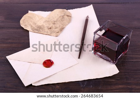 Envelope with pen and ink on wooden background