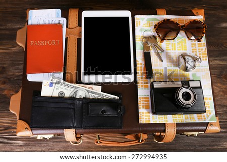Packed suitcase of vacation items on wooden table, closeup