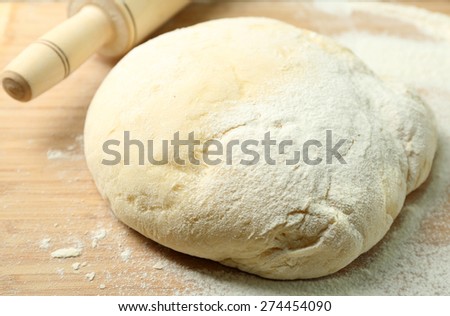 Dough on cutting board with rolling pin close up