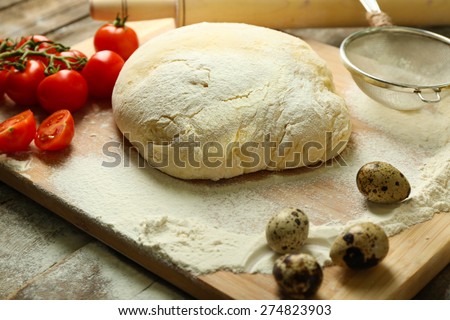 Dough on cutting board with cherry and quail eggs on table close up