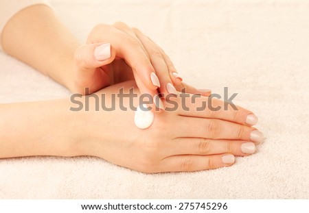 Woman caring hands with cream on fabric background