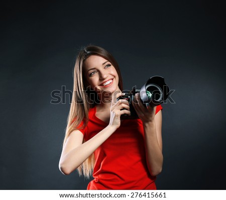 Young female photographer taking photos on black background