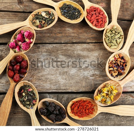 Collection of tea and natural additives in wooden spoons, on old wooden table