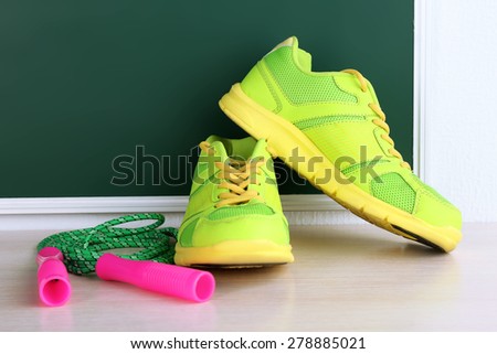 Sport shoes and skipping rope on blackboard background