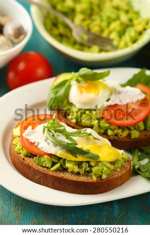 Tasty sandwiches with egg, avocado and vegetables on plate, on wooden background