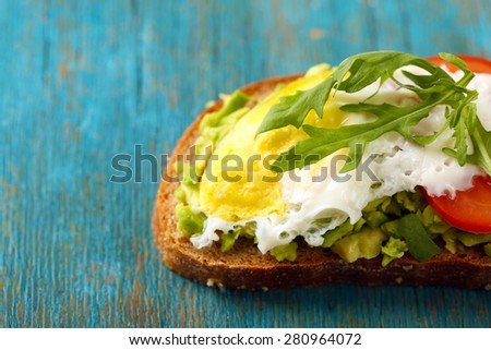 Tasty sandwich with egg, avocado and vegetables on wooden background