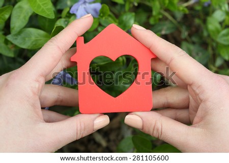 Female hands holding toy house outdoors
