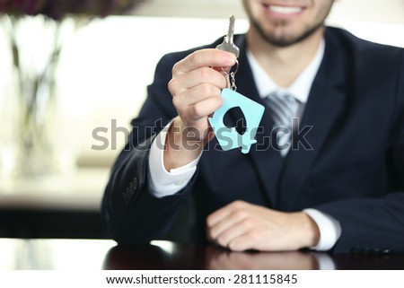 Portrait of businessman with keys in hand in office on blurred background