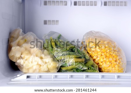 Frozen vegetables in bags in freezer close up