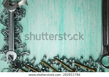 Screw nuts and wrenches frame, on color wooden background
