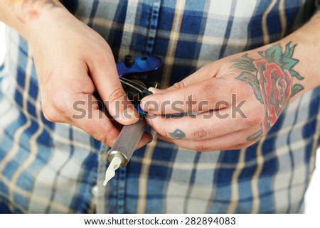 Hand of tattoo artist with tattoo machine, closeup