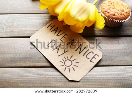 Fresh cupcake, tulips and Have A Nice Day massage on wooden background