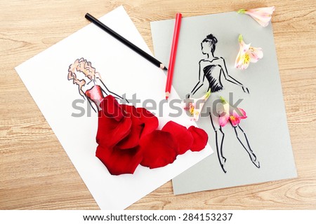 Pictures with flower petals and pencils on wooden table