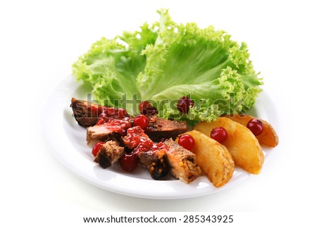 Beef with cranberry sauce, roasted potato slices on plate, isolated on white