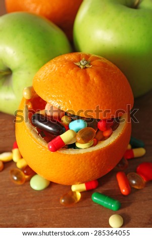 Orange fruit filled colorful pills, on wooden background