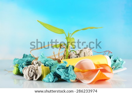 Pile of rubbish with plant on blue background