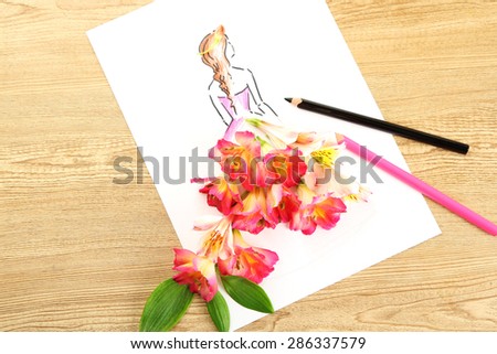 Picture with flower petals and pencils on wooden table