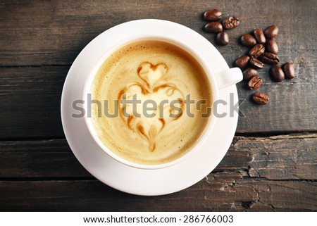 Cup of coffee latte art with grains on wooden background
